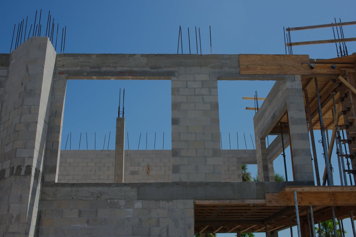 New house structure under construction with tall walls and stacked materials